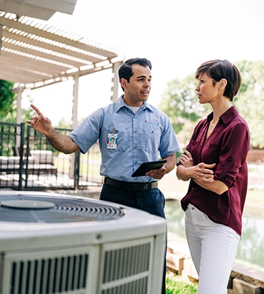 Aire Serv tech showing female customer outside air conditioner.