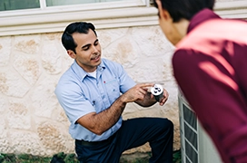 Aire Serv tech showing capacitor to customer.