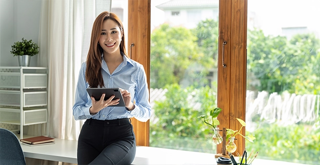 An asv technician holding a tablet and smiling by a window.