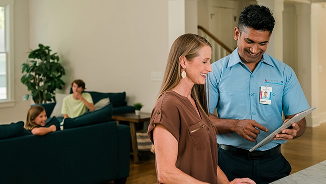 Technician talking to lady in kitchen.