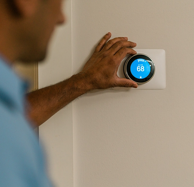 Aire Serv technician adjusting the thermostat.