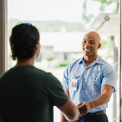 Aire Serv tech shaking hands with customer in doorway.