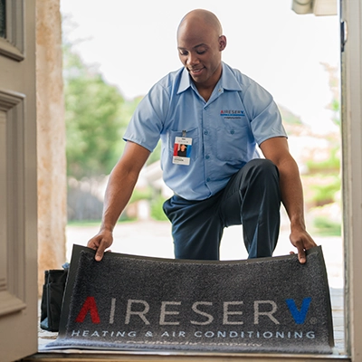 Aire Serv tech placing floor mat in doorway.
