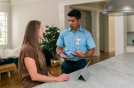 Aire Serv tech talking with customer leaning on kitchen countertop.