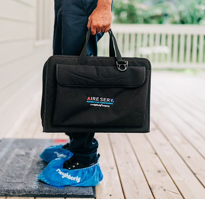 Aire Serve professional with neighborly shoe covers on.