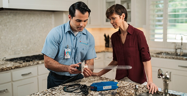 Aire Serv professional talking with client in the kitchen.