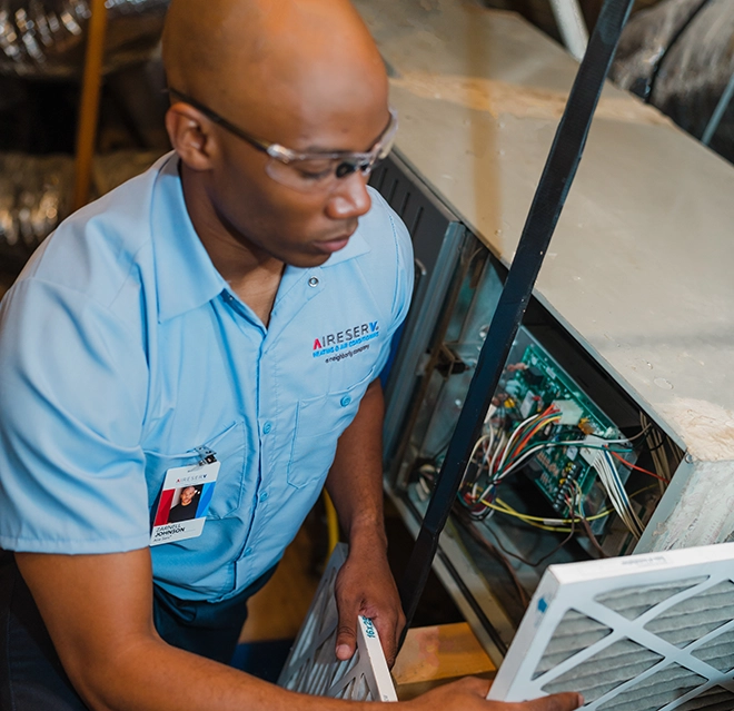 Aire Serv Professional working on air filter.