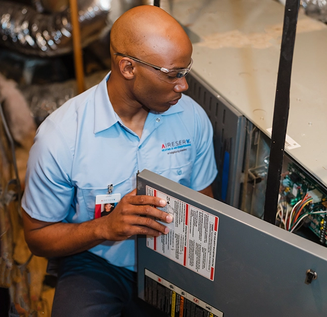 Aire Serv professional doing repair work on a furnace.